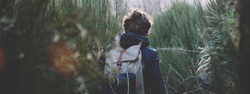 Young girl walking among huge grass in mountains with backpack in jacket. Cool weather.. Wide screen panoramic