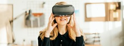 Portrait of pretty woman using virtual headset sitting at workplace