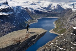 Hiker walking to the edge of Trolltunga rock, Norway