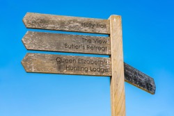 Wooden sign post with directions against blue sky in Epping Forest in Essex, England