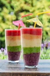 Rainbow layered fruit smoothie on garden table