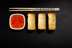 Baked spring rolls with deep, rice and vegetables, on a black plate