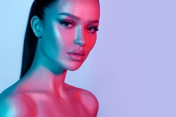 High fashion model metal silver lips and face woman in colorful bright neon UV blue and purple lights, posing in studio, beautiful girl, glowing makeup, colorful makeup. Glitter Bright Neon Makeup
