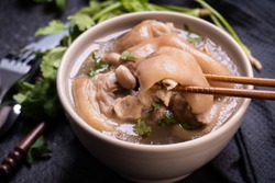 Top view, close up, copy space, Taiwan asian distinctive street food, peanut pork knuckle soup in a beige ivory creamy-white colored bowl isolated on dark shale slate table