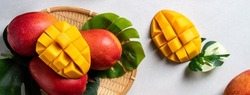 Mango background design concept. Top view of diced fresh mango fruit pattern with leaves on gray table.