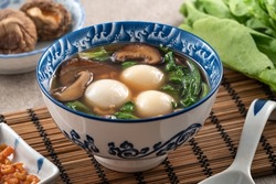 Eating big tangyuan yuanxiao (tang yuan, glutinous rice dumpling balls) with savory soup in a bowl for Winter solstice festival.