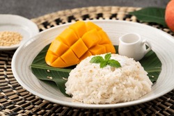 Delicious Thai mango sticky rice with cut fresh mango fruit in a plate on gray table background.