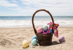 Beach Happy Easter background with basket and color eggs near ocean