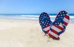 Patriotic USA background with flip flops on the sandy beach