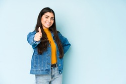 Young indian woman isolated on blue background smiling and raising thumb up