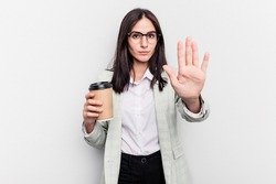 Young business caucasian woman holding takeaway coffee isolated on white background standing with outstretched hand showing stop sign, preventing you.