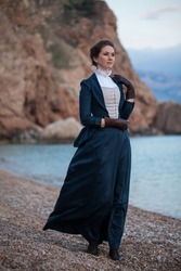 Romantic young beautiful lady wearing victorian dress looking  at the sea. Vintage style. Steampunk concept