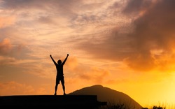 Strong man with fist in the air standing on top a mountain. Triumph, victory and feeling determined.
