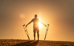 Man letting go of crutches able to walk again. Body recovery, healing, and miracle concept. 