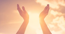 Hands lifted up to the sunrise sky touching the warm rays of sunlight. Hope and salvation concept. 