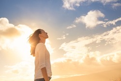 Attractive young woman looking up to the beautiful sky with feelings of hope and happiness. 