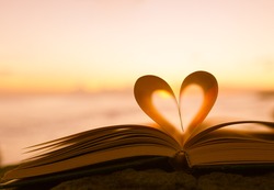 Heart from a book page against a beautiful sunset. 