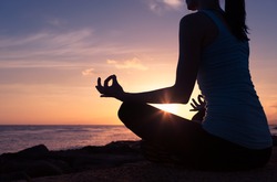 Young woman meditating in a beautiful sunset setting. 