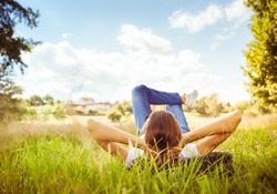 Young woman lying on grass looking up in the sky. People relaxing in outdoors. 