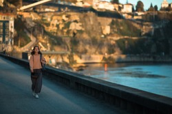 A young woman walks along the city's river embankment. Porto, Portugal.
