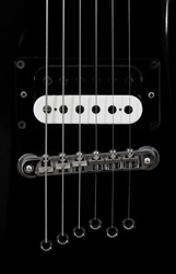 Part of a black electric guitar close-up.