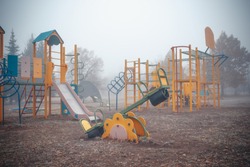 Empty children's playground on a foggy autumn morning.