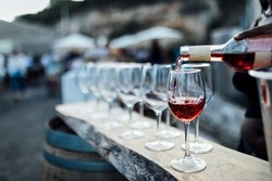 POURING RED WINE AT SOCIAL EVENT LIFE WEDDING PARTY OR OTHER LUXURY EVENT.