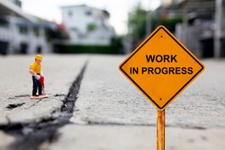 small figure of a man digging concrete street with Work in Progress message.