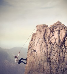 Young businessman scaling a rock