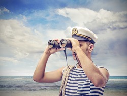 young sailor looks through binoculars