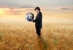 Businessman on a wheat field holding the Earth