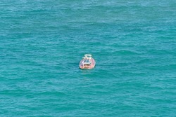 Small white and orange raft lost in the middle of the sea, with no people, just the raft surrounded by water.