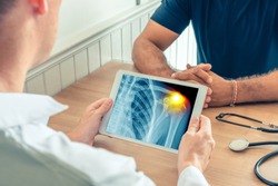 Doctor holding a digital tablet with x-ray of the chest of the patient with pain on the shoulder