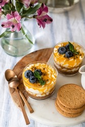 Passion fruit mascarpone cheese desserts served in individual cups and garnished with blueberries and mint leaves.