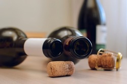 Empty wine bottles and corks lie on the table, close-up. Concept of unhealthy lifestyle.