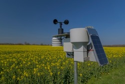 Smart agriculture and smart farm technology. Meteorological instrument used to measure the wind speed and solar cell system in the raps field. Weather station with solar panel placed in the field.