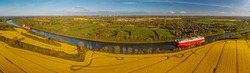 Panorama view of Kiel Canal with container ship and ferry with raps fields along canal. Container cargo ship and ferry on the Kiel Canal between Baltic sea and North Sea Schleswig Holstein, Germany.