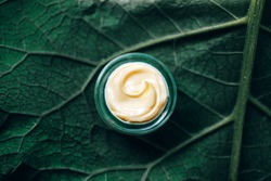 Texture of natural cosmetic cream for body care on a green leaf. Natural organic cosmetics from plants for skin care