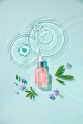 Moisturizing cosmetic products on water with drops. Serum glass bottle and cream jar on aqua surface with waves in sunlight. Concept for advertising organic moisturizing skin care, spa.