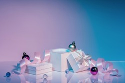 White rectangular podium with satin ribbon, gift boxes, Christmas balls Neon background