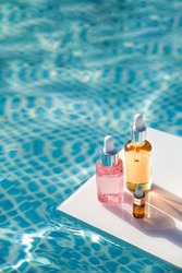 Different packages of cosmetics tanning oil on background of blue water on sunny summer day