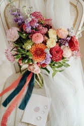 expensive wedding bouquet with beautiful flowers on a white vintage chair against the background of the bride's veil. An invitation with wedding rings lies on a chair next to a wedding bouquet.
