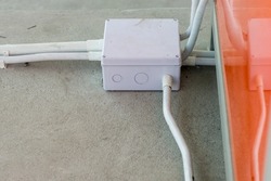 Square Flooring box with plastic pipes and electric cables. White electrical junction box and wires on the floor.  Installation of electrical wiring on the concrete floor. 