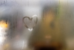 A heart painted on a misted window. Heart on misted glass. Heart on a window background. Heart symbol of love drawn on the glass.