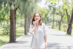 Woman walking in the park having sunstroke in summer hot weather, Young pretty girl drying sweat using a wipe on a warm summer day in a park