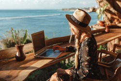 Business woman working with computer on the beach.  Freelance concept. Pretty young woman using laptop in cafe on tropical beach