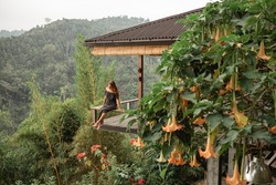 Young beautiful woman is sitting on a balcony in a wooden house overlooking the mountains