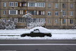 A view across the road of a car in a winter snow city