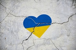 The symbol of the national flag of Ukraine in the form of a heart on a cracked concrete wall. Concept.
