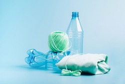 The concept recycling plastic. Empty plastic bottle and recycled polyester fiber, synthetic fabric blue background